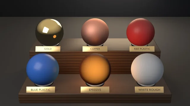 Six material spheres in gunmetal collars on a two-tier walnut riser, each over an engraved brass plaque: gold, copper, red plastic behind; blue plastic, emissive, white rough in front.